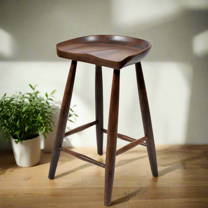 A brown solid wood bar stool with a smooth seat and tapered legs.